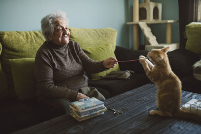 Senior woman playing with her kitten at home