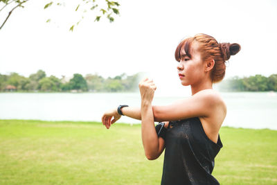 Young woman looking at lake against sky