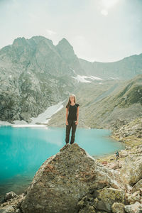 Man standing on rock by mountains against sky