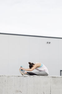 Side view of woman lying on wall