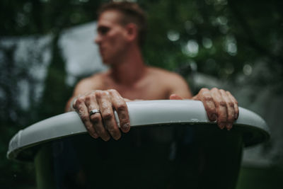 Midsection of shirtless man holding mobile phone