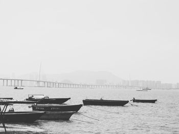 Boats moored in sea against sky during foggy weather