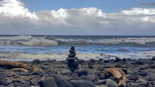 Stack of pebbles on beach against sky