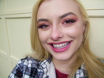 Portrait of smiling young woman standing against wall