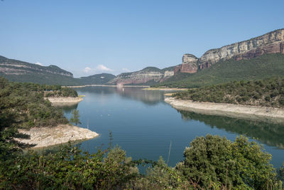 Scenic view of lake and mountains against clear blue sky