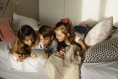 Children on bed using digital tablet