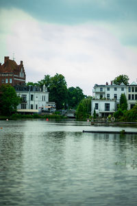 Buildings by lake against sky