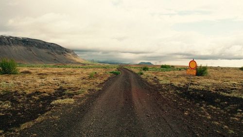 Road passing through landscape against cloudy sky