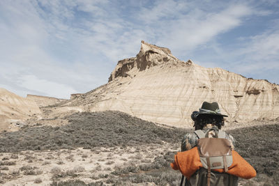 Rear view a traveler taking pictures with a backpack in the bardenas desert. navarre