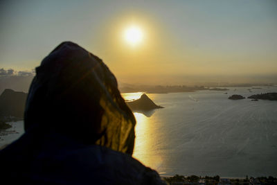 Rear view of man looking at sea against sky