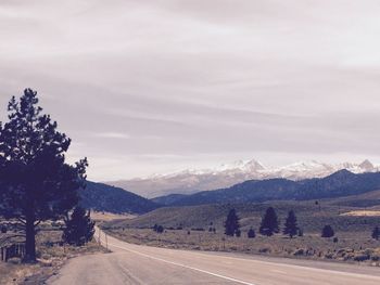 Empty road along landscape and mountains against sky