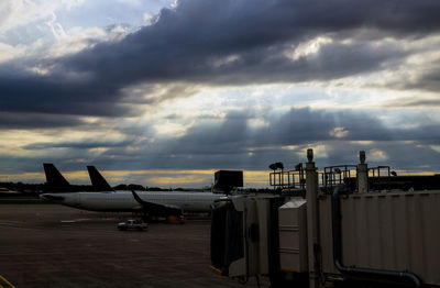 Airplane on airport runway against sky at sunset