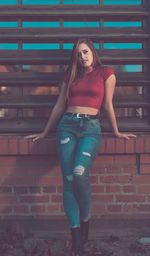 Portrait of young woman standing against brick wall