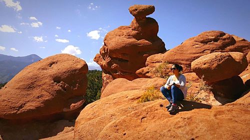 Men on rock in mountains against sky