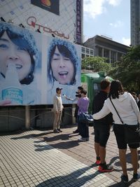 People standing on footpath by building