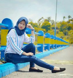Full length of woman sitting on seat at playground