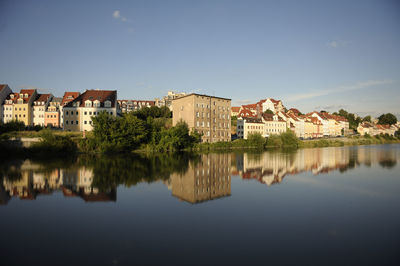 Reflection of houses in lake against clear sky