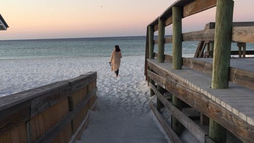 Rear view of woman on beach against sky