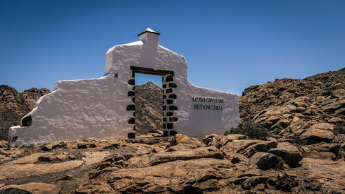 Low angle view of cross on rock against sky