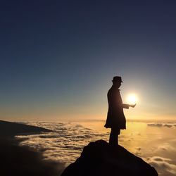 Silhouette of woman standing on landscape at sunset