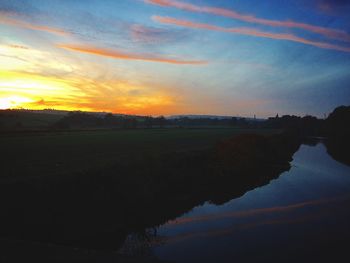 Scenic view of farm against sky during sunset