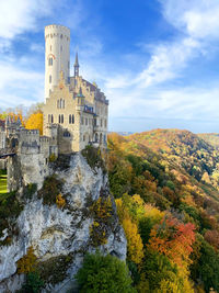 Historic building against sky with autumn forest