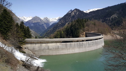 Scenic view of dam and mountains against sky