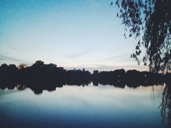 Reflection of silhouette trees in lake against sky