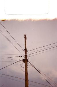 Low angle view of electricity pylon on street against sky