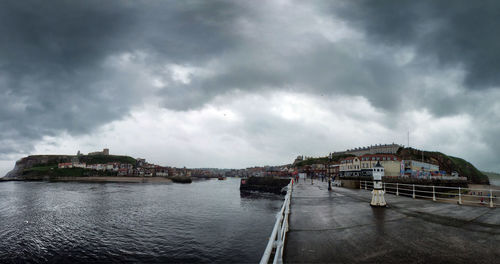 Bridge over lake against cloudy sky