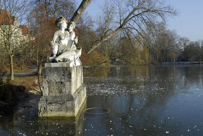 Statue by lake against sky