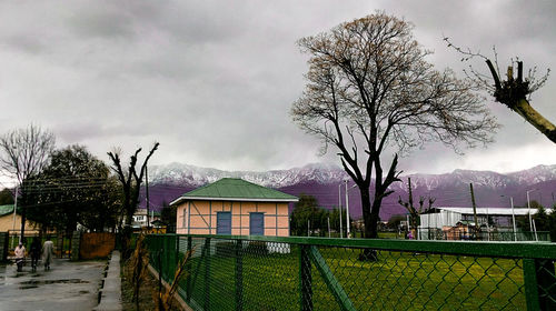 Houses on field against cloudy sky