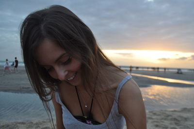 Beautiful woman on beach against sky during sunset