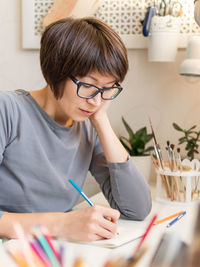 Woman drawing on book at home