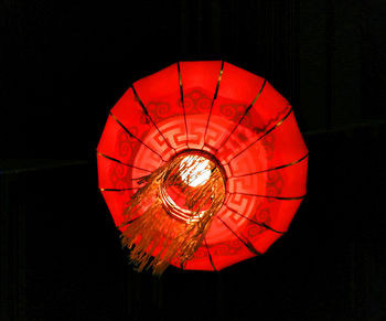 Low angle view of illuminated lantern hanging against black background