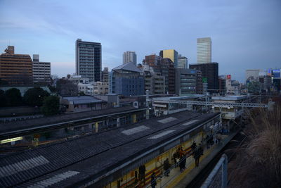 High angle view of railroad tracks by buildings in city against sky