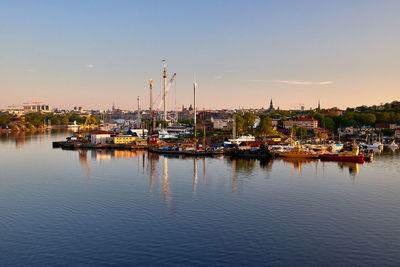 Sailboats moored at harbor against sky during sunset