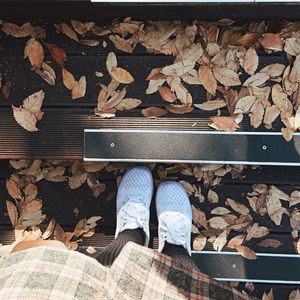 Low section of person standing on dry leaves during autumn