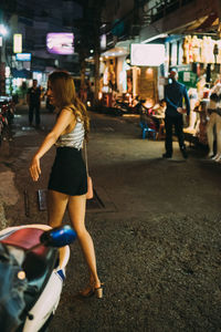 Woman walking on road in city at night