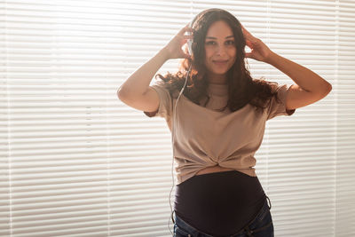 Portrait of young woman standing against wall