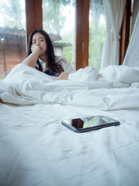 Woman looking at mobile phone on bed