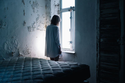 Rear view of woman looking towards window at home