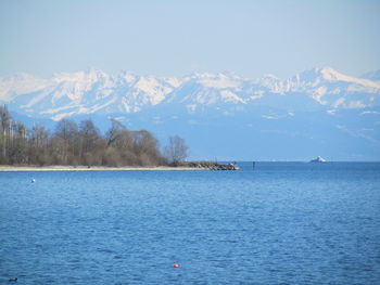 Scenic view of lake by snowcapped mountains against sky