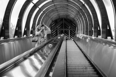 Woman photographing on escalator