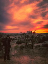 Man standing on field against orange sky