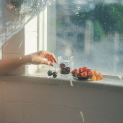 Midsection of person with ice cream in glass at home