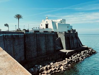 Lighthouse by sea against sky