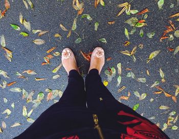 Low section of woman standing on autumn leaves