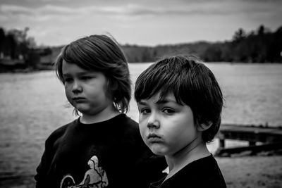 Portrait of boy with sibling against lake at dusk