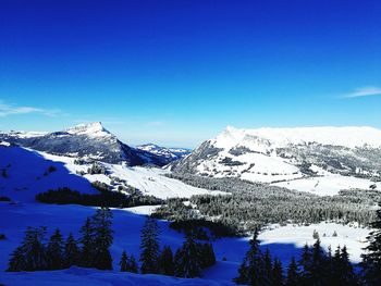 Scenic view of snow mountains against blue sky